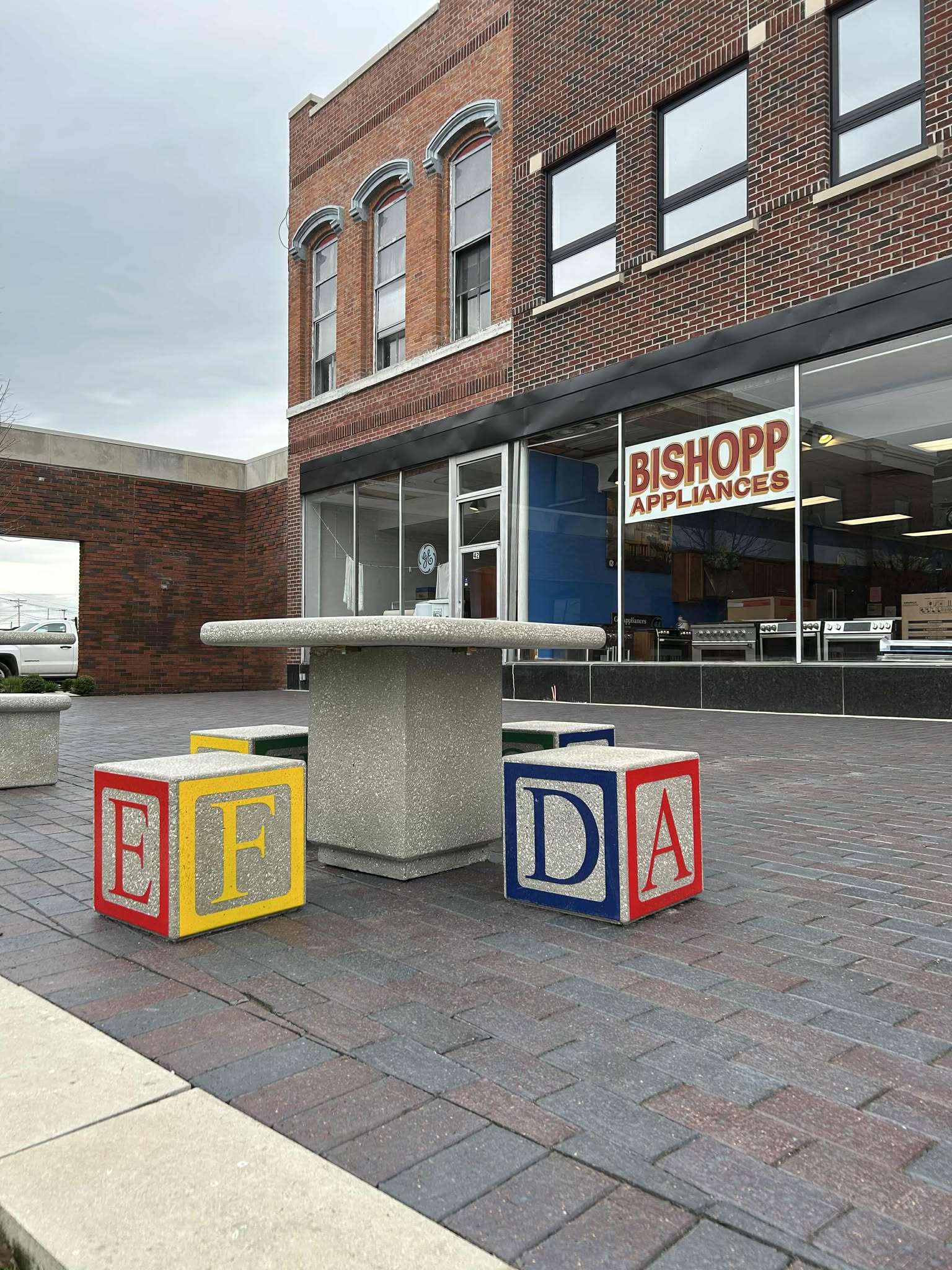 outdoor concrete furniture next to downtown square with construction workers in background